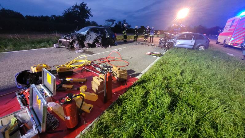 Momentaufnahme an einer Einsatzstelle. Verkehrsunfall mit zwei Fahrzeugen. Rettungsgeräte im Vordergrund.