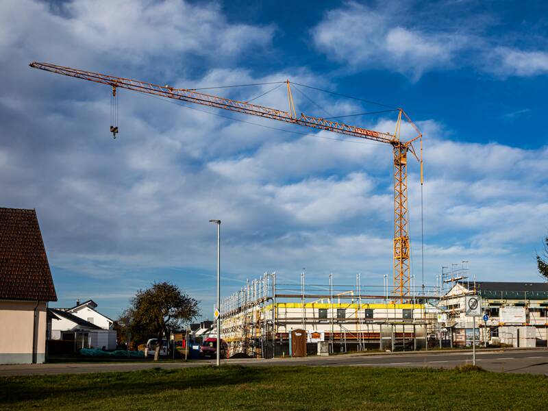 Ein gelber Baukran bei einer Baustelle für ein Haus.