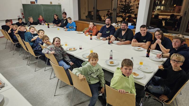 Jugendfeuerwehr und Aktive bei gemeinsamen Essen am Tisch