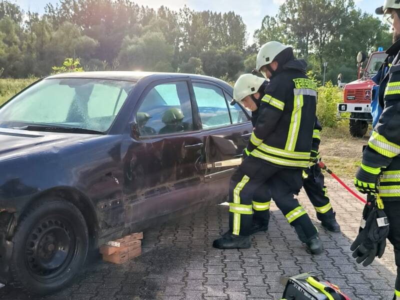 Zwei Feuerwehrkräfte öffnen mit hydraulischem Rettungsgeräte eine PKW-Tür